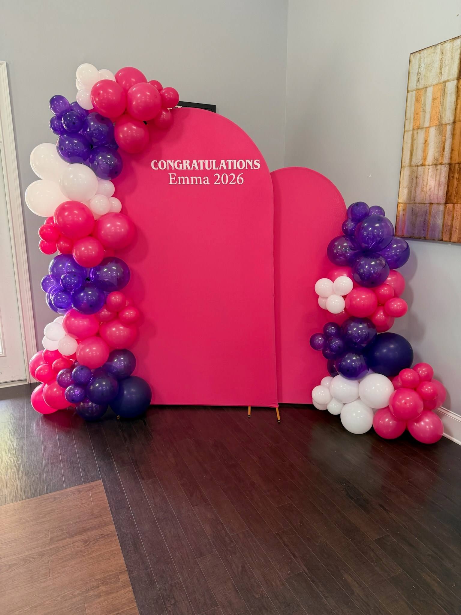 A hot pink arch reading Congratulations, framed by a hot pink, purple and white balloon garland