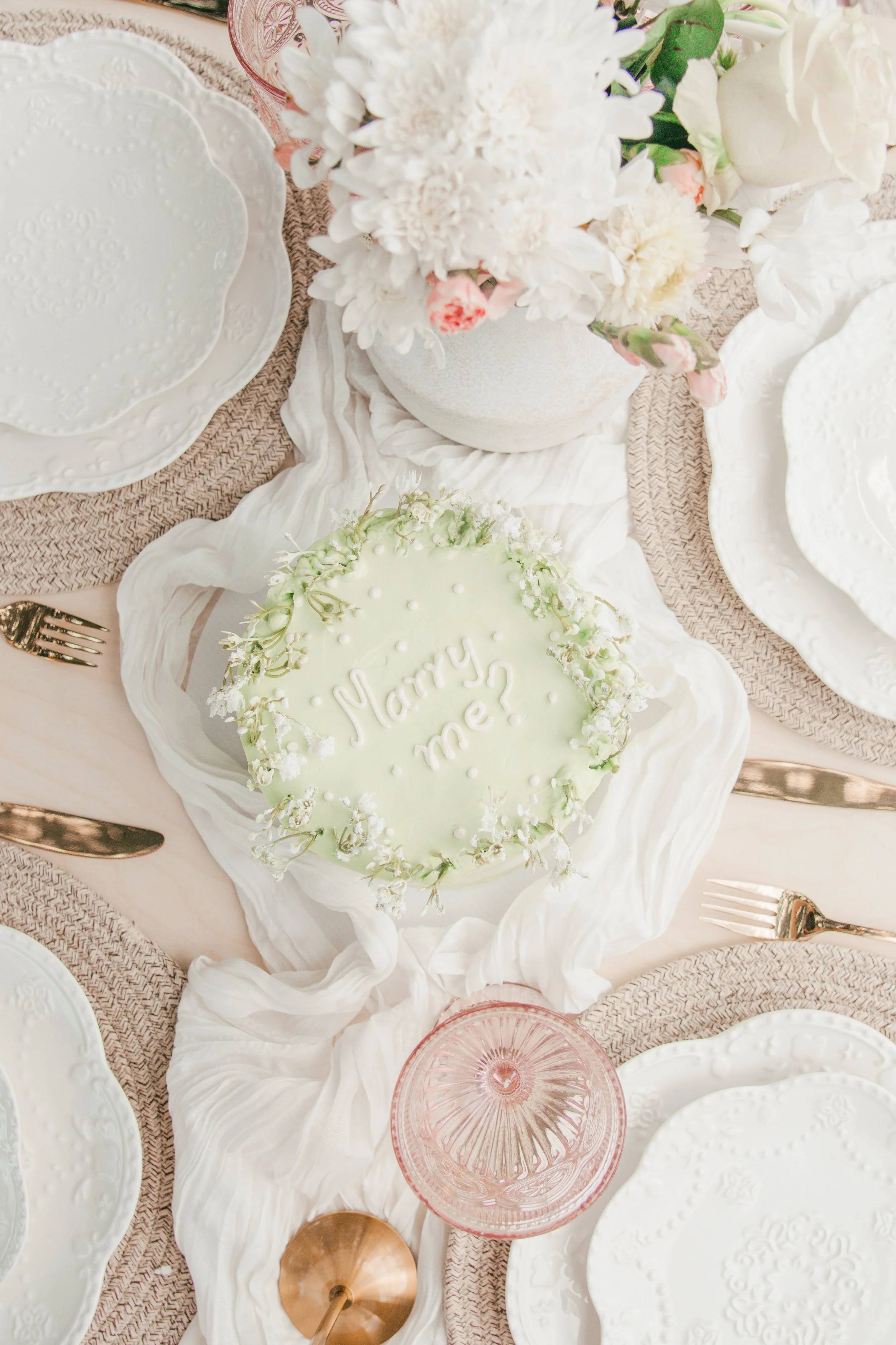 Scalloped white plates on pink and cream linens, seen from above