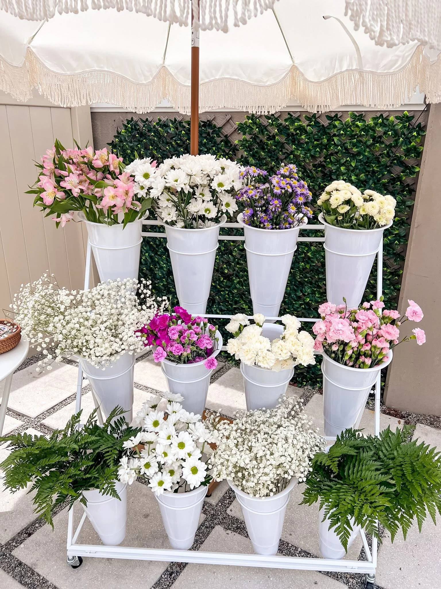 A Bloom Bar flower cart of white buckets filled with pink, white and green blooms
