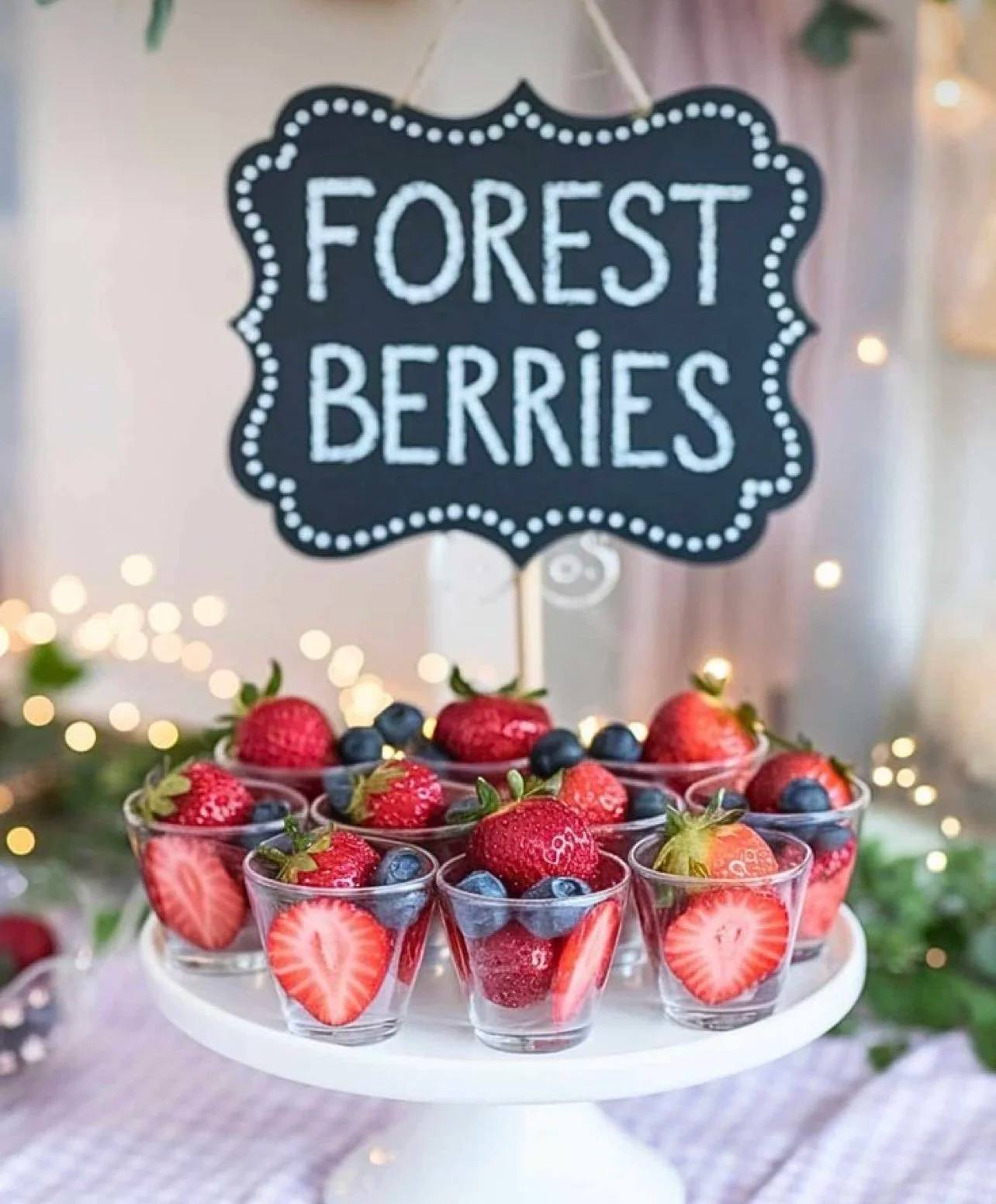 Cups of strawberries and blueberries under a chalkboard sign reading Forest Berries