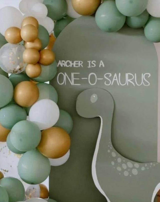 Jurassic Adventure kids party: a sage dinosaur backdrop with green, gold and white balloons
