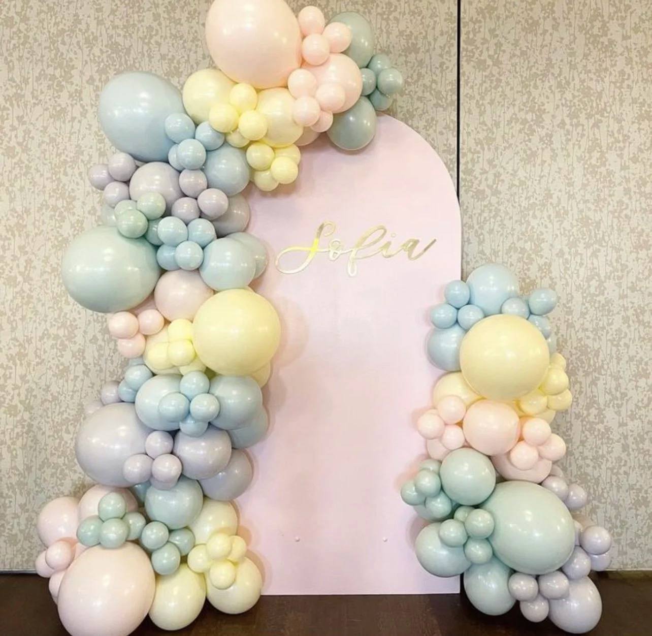 Pastel balloon garland in blush, mint, lilac and butter yellow on a pink arched backdrop with gold Sofia lettering